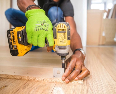 person-using-dewalt-cordless-impact-driver-on-brown-board